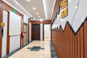 A hotel lobby with a marble floor, wooden paneling, and directional signs indicating the fifth floor. - MG Crown Hotel 1 (Madinah)