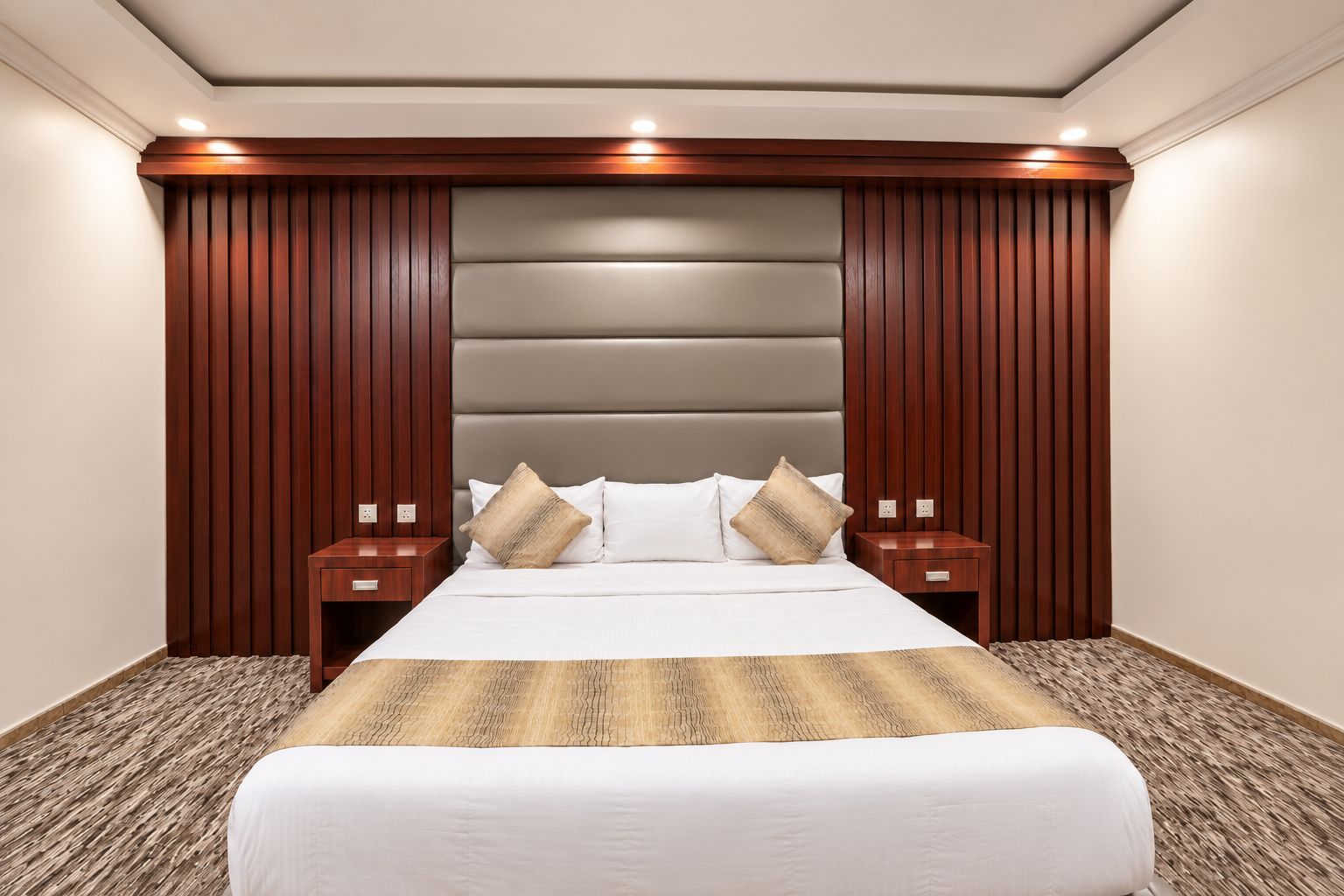 Een hotelkamer met een groot bed, houten lambrisering en twee nachtkastjes.