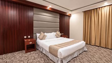 Ein Hotelzimmer mit einem großen Bett, einem Holznachttisch, einem Kopfteil mit vertikalen Lamellen und einem beigen Teppich.