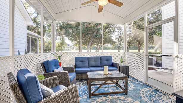 A covered patio area with wicker furniture, a blue sofa, and a coffee table. - Golf Getaway w/ Resort Perks in North Myrtle Beach (North Myrtle Beach)