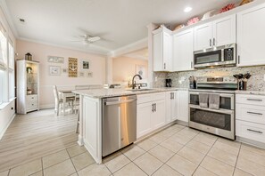 A modern kitchen with white cabinets, stainless steel appliances, and a central island.