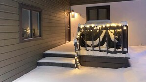 En snötäckt veranda med en bänk och ljusslingor.