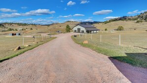 A rural road leading to a single-story building with a dark roof and a garage. - On 90 Scenic Acres! Rural Hot Springs Retreat (Hot Springs)
