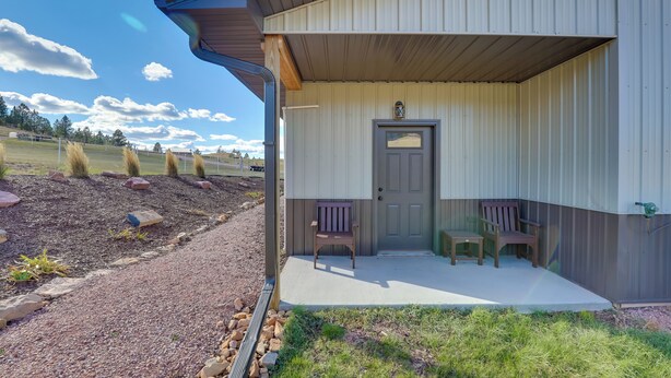 A building with a covered porch, two wooden benches, and a door. - On 90 Scenic Acres! Rural Hot Springs Retreat (Hot Springs)