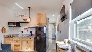 A modern kitchen with wooden cabinets, a black refrigerator, a microwave, and a TV mounted on the wall. - On 90 Scenic Acres! Rural Hot Springs Retreat (Hot Springs)