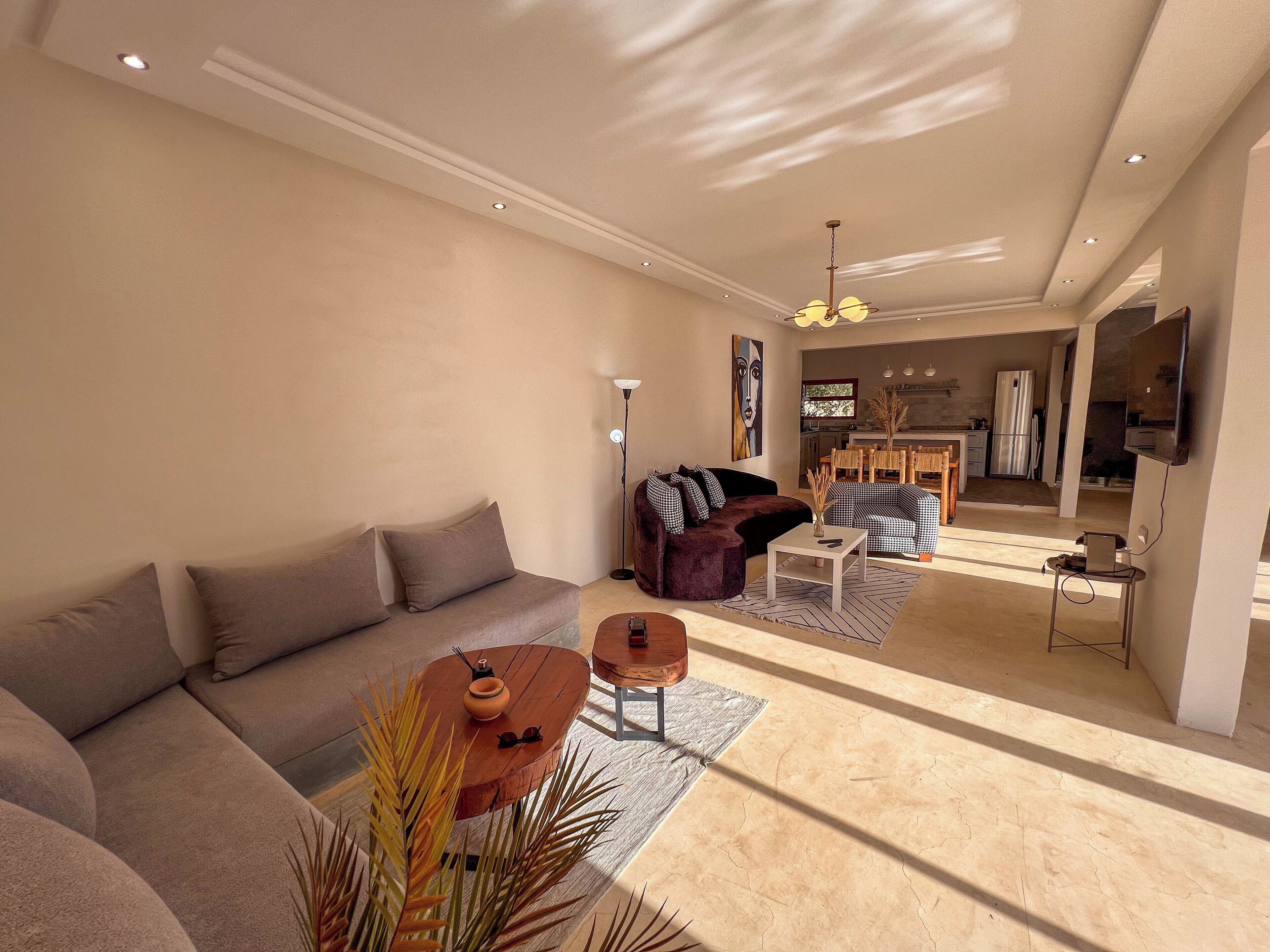 A modern living room with a sofa, a coffee table, and a dining area with chairs.