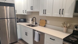 A modern kitchen with white cabinets, stainless steel appliances, a sink, and a stove.
