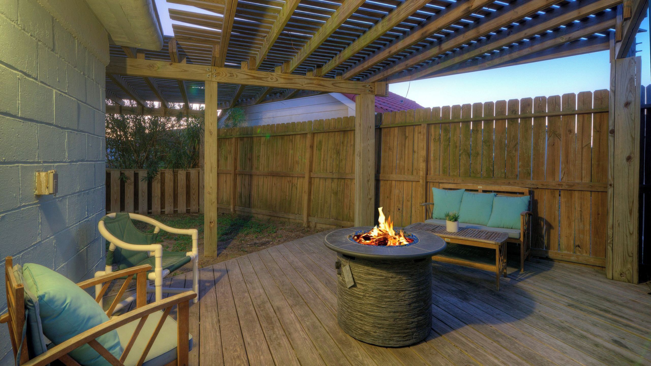 A wooden deck with a fire pit, outdoor seating, and a pergola.