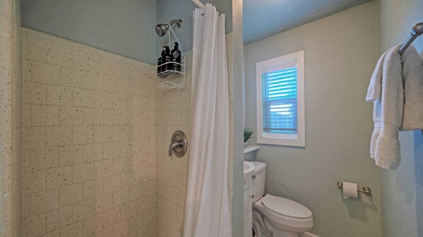 A bathroom with a shower, toilet, and a window with blinds. - Walk to Shops, Near Dining & Beach Central Port A Location Casa Coconut by Avantstay (Port Aransas)