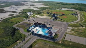 Vista aérea de un complejo deportivo con piscina, campo de béisbol y zona de estacionamiento.