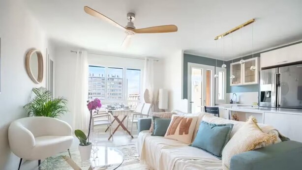 Una sala de estar moderna con una mesa de centro de vidrio, un sofá blanco y una zona de comedor con una mesa y sillas.
