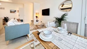 Una sala de estar moderna con comedor, un ventilador de techo, un televisor de pantalla plana y un espejo grande.