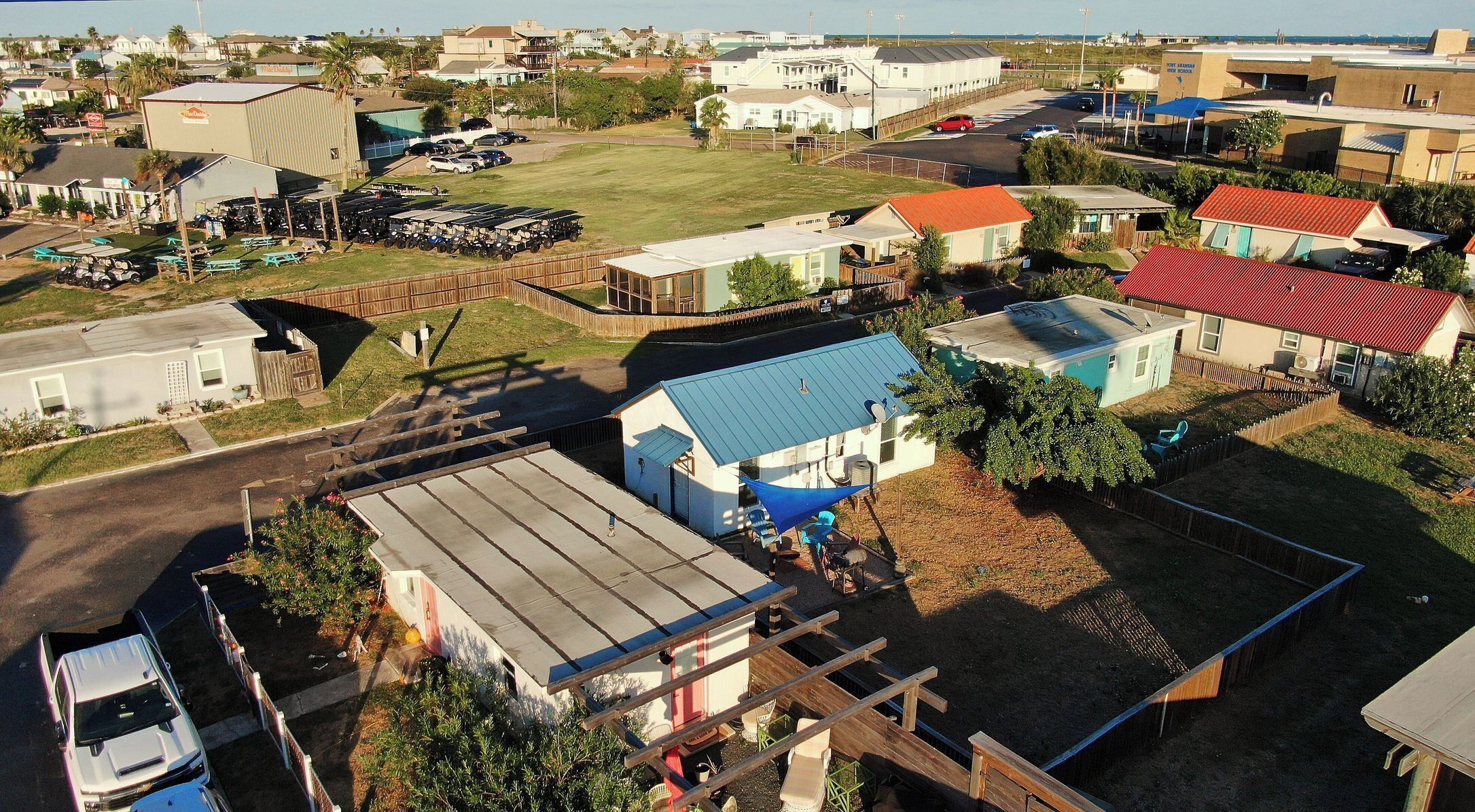 Uma área residencial com casas, um estacionamento e um pequeno edifício com telhado azul.