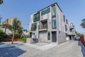 Ein modernes, zweistöckiges Gebäude mit Betonfassade, großen Fenstern und einem sichtbaren Balkon.