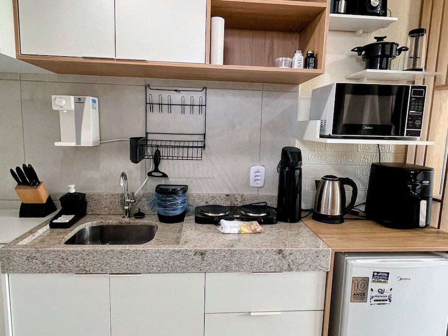 A compact kitchen with a built-in microwave, a coffee maker, and a refrigerator.