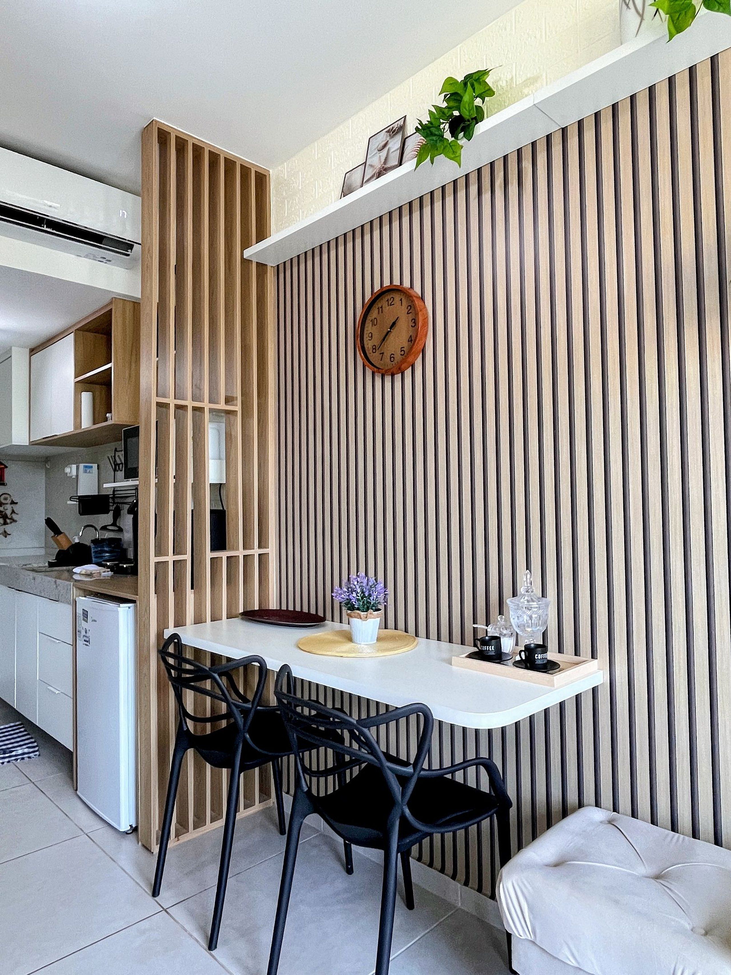 Cozinha moderna com geladeira embutida, armário de madeira e área de refeições com mesa branca e cadeiras pretas.