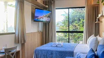 Een hotelkamer met een bed, bureau, televisie en een groot raam.