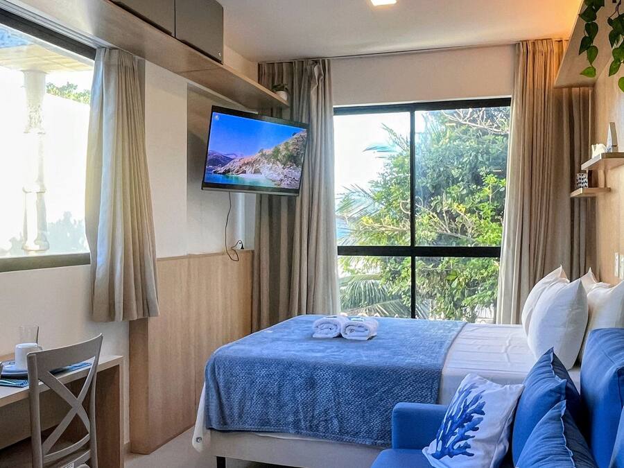 A hotel room with a bed, a desk, a TV, and a large window.