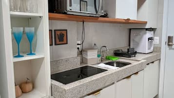 A compact kitchen with a microwave, coffee maker, and a sink.