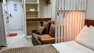 A hotel room with a bed, a sofa, a wardrobe, and a kitchenette.