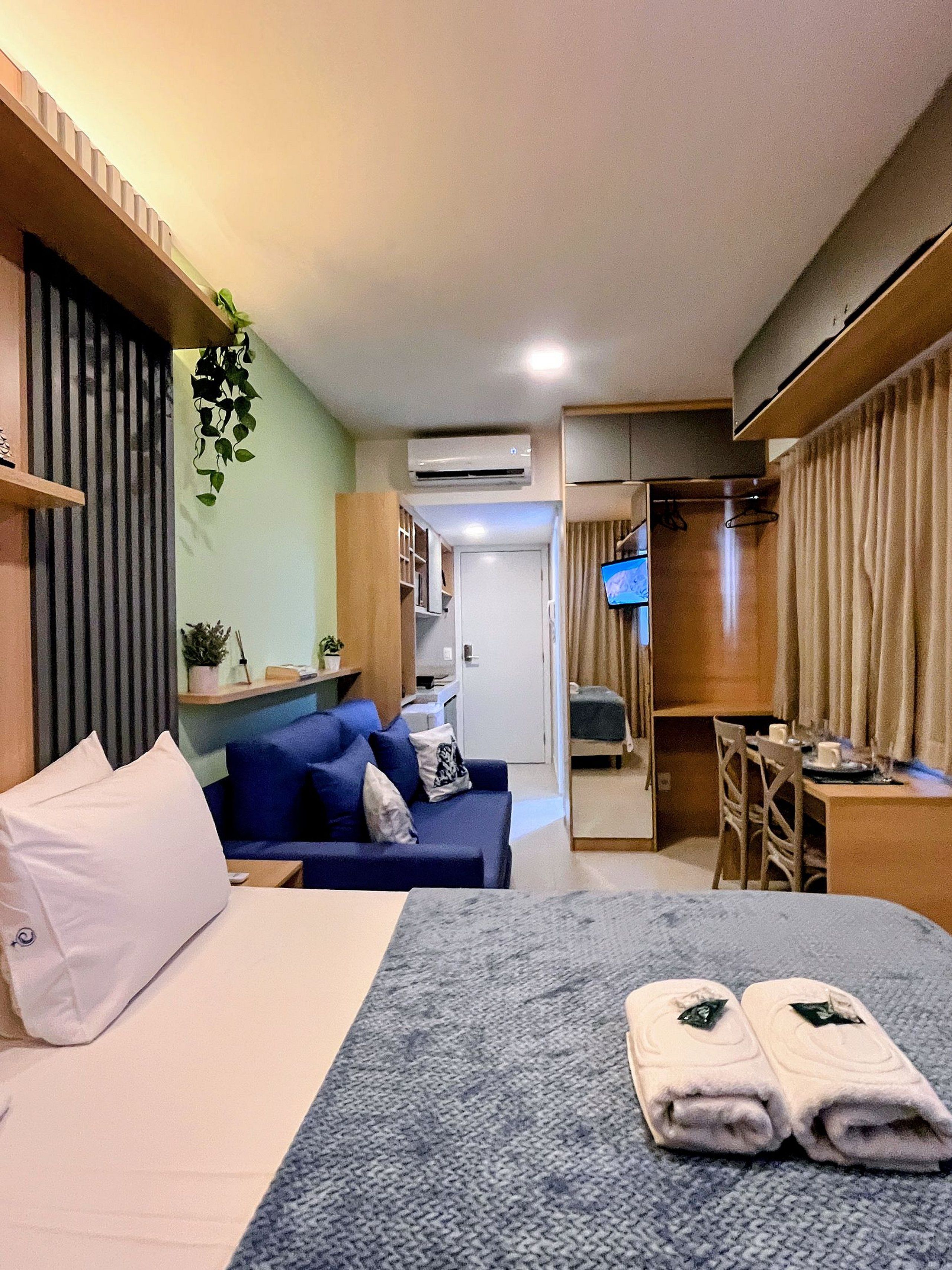 Une chambre d’hôtel comprenant un lit, un coin salon avec un canapé, un bureau, une télévision et une armoire.