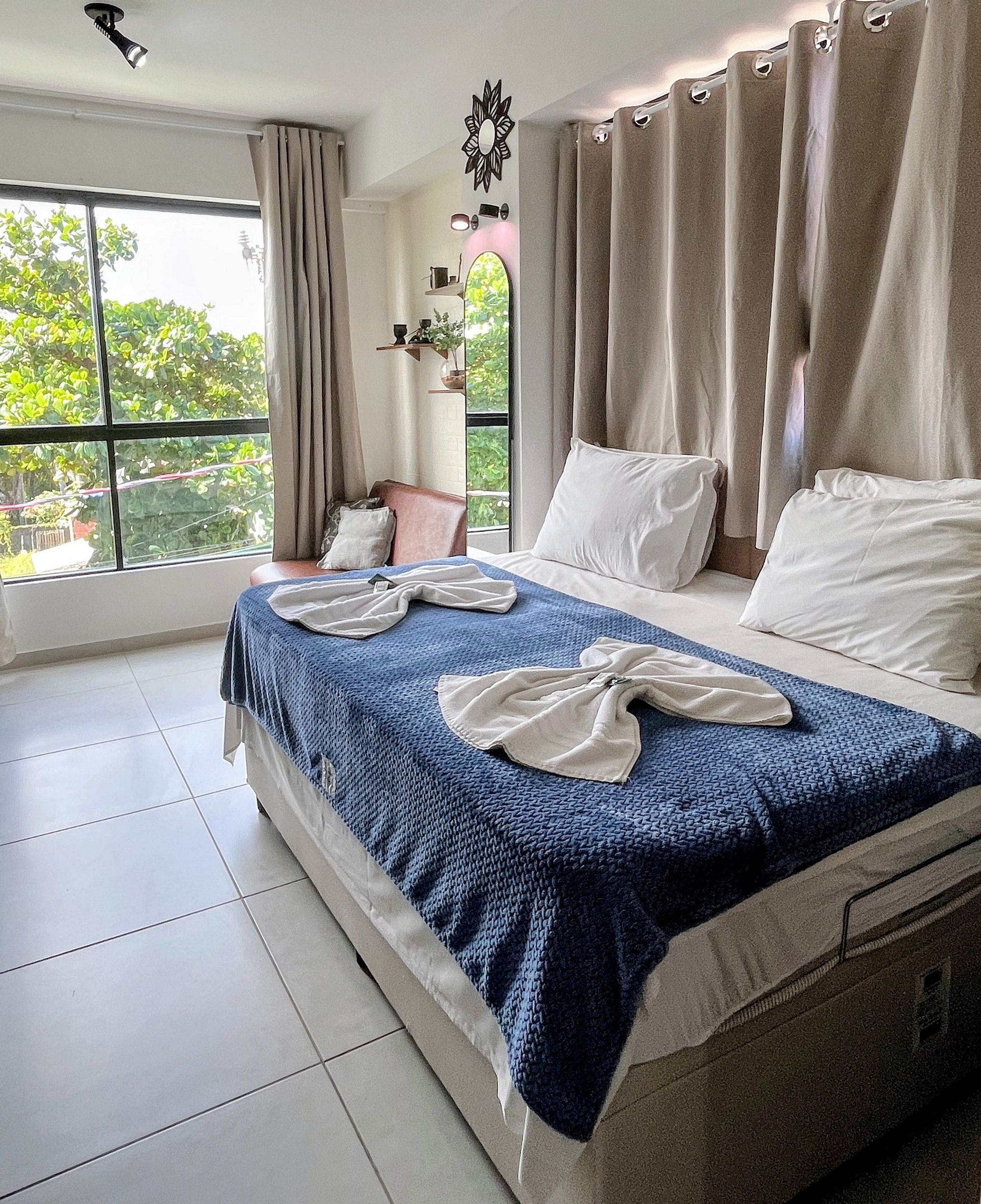 Habitación de hotel con una cama grande, vista a áreas verdes y un ventilador de techo.