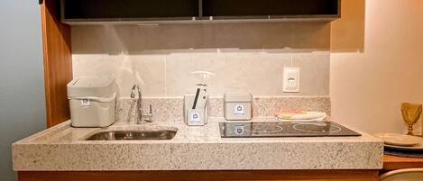 A compact kitchen with a sink, countertop, and built-in cabinets.