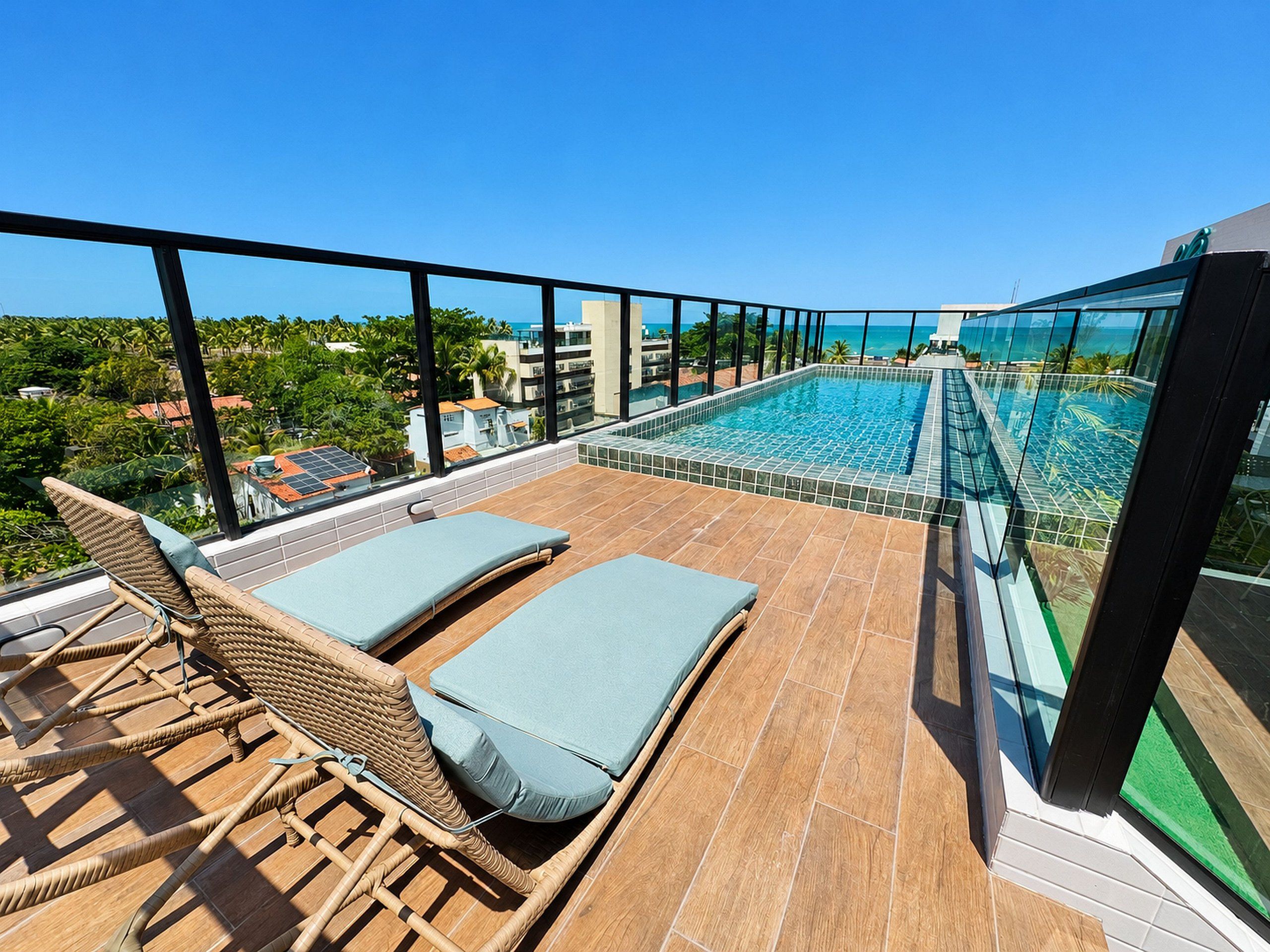 Zona de piscina en la azotea con sillones y vista al océano.