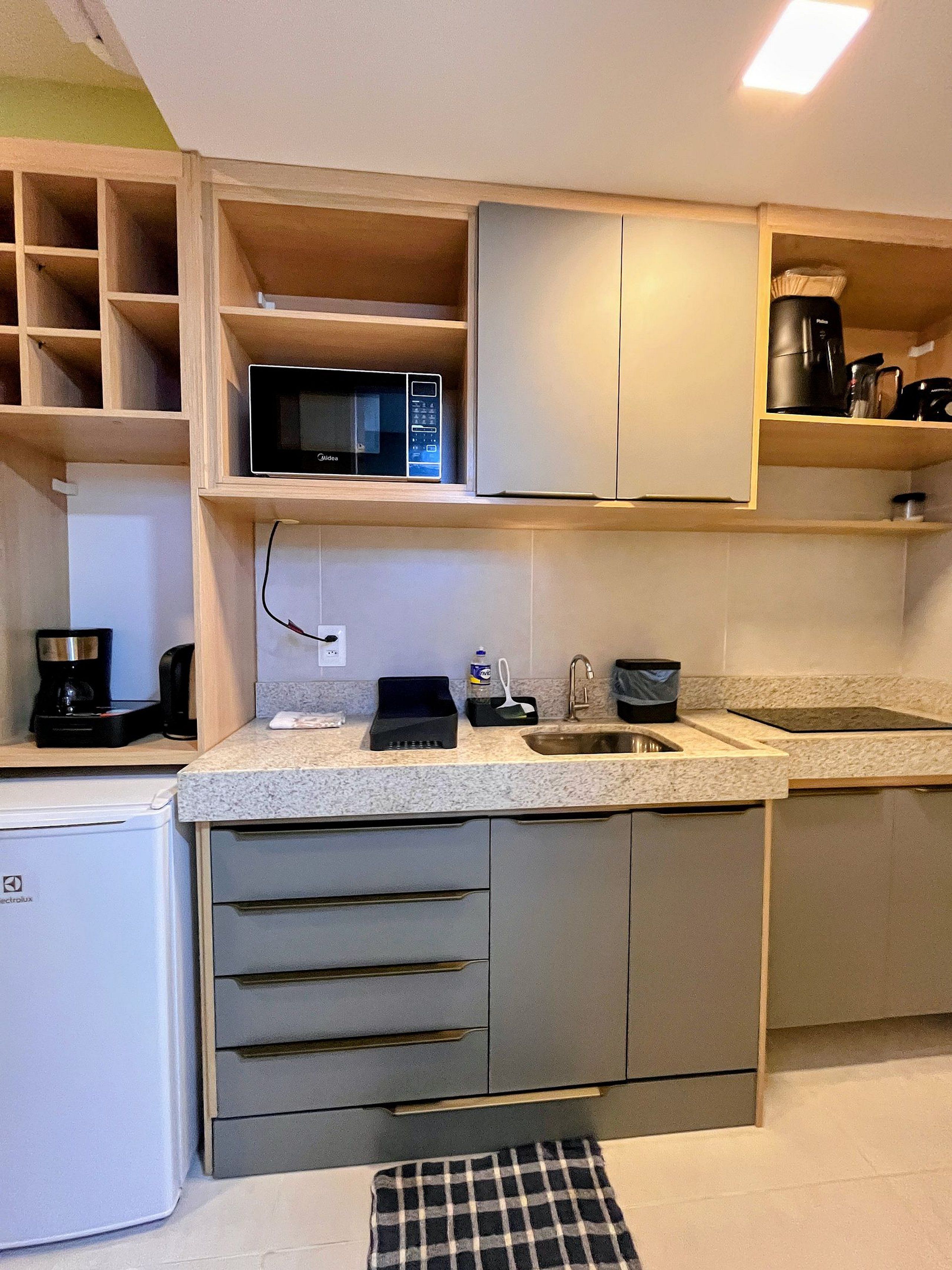Een kleine keuken met een magnetron, koffiezetapparaat en een koelkast.
