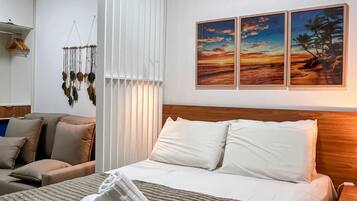 Een hotelkamer met een bed, een slaapbank, een aan de muur hangend kunstwerk en een macramé decoratie.