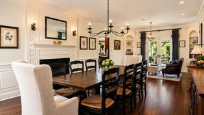 A dining room with a large wooden table, black chairs, a chandelier, and a fireplace. - Hawk’s Landing | Hot Tub, Views & Game Room (Banner Elk)