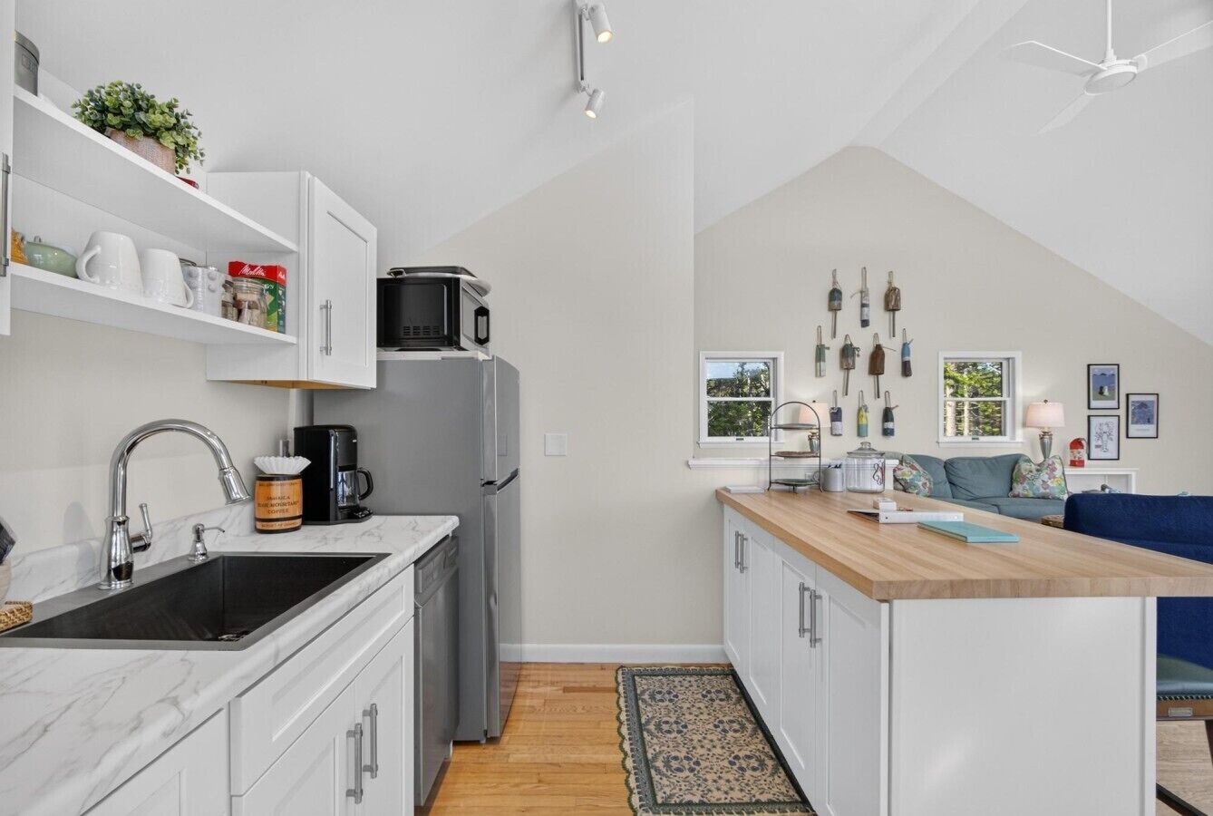A compact kitchen with white cabinets, a black sink, a microwave, and a coffee maker.