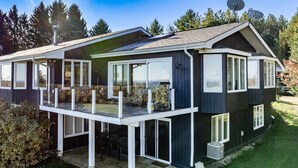 Et moderne hus i to etager med stor terrasse, skydedøre og parabolantenner.