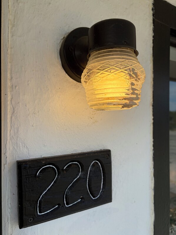 A house number sign with the number 220 on a white wall.