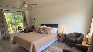 A bedroom with a bed, a chair, a desk, a lamp, and a ceiling fan.