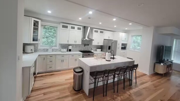 Una cucina moderna con mobili bianchi, un'isola centrale e un angolo bar.