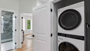 Una lavanderia moderna con lavasciuga affiancate, cabina doccia in vetro e vista sull'esterno.