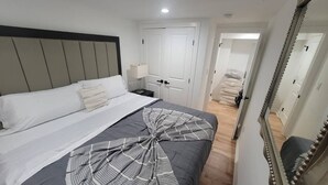 Ein Hotelzimmer mit einem Bett, einem Nachttisch, einem Spiegel und einer Tür zu einem anderen Raum.