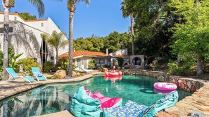 A swimming pool with lounge chairs, a stone wall, and a small building with a tiled roof. - Private Malibu Escape w/ Guest House, Fire Pits & Mountain Views The Malibu Retreat by Avantstay (Calabasas)