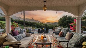 A covered outdoor seating area with a view of mountains, a fire pit, and a variety of seating options. - Private Malibu Escape w/ Guest House, Fire Pits & Mountain Views The Malibu Retreat by Avantstay (Calabasas)