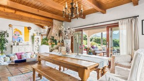 A spacious living area with a wooden table, comfortable seating, and a large window offering a view of the outdoors. - Private Malibu Escape w/ Guest House, Fire Pits & Mountain Views The Malibu Retreat by Avantstay (Calabasas)