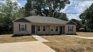 A single-story house with a front porch, a driveway, and a lawn.