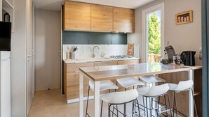 Une cuisine moderne avec des meubles en bois, un plan de travail en marbre et un îlot central doté de tabourets de bar.