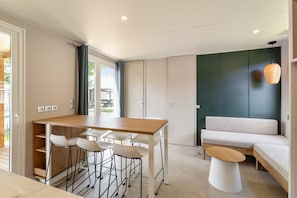 A modern kitchen with a dining area, a sofa, and a hanging light fixture.
