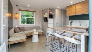 Une cuisine moderne avec un plan de travail en bois, des tabourets de bar blancs et un micro-ondes encastré.