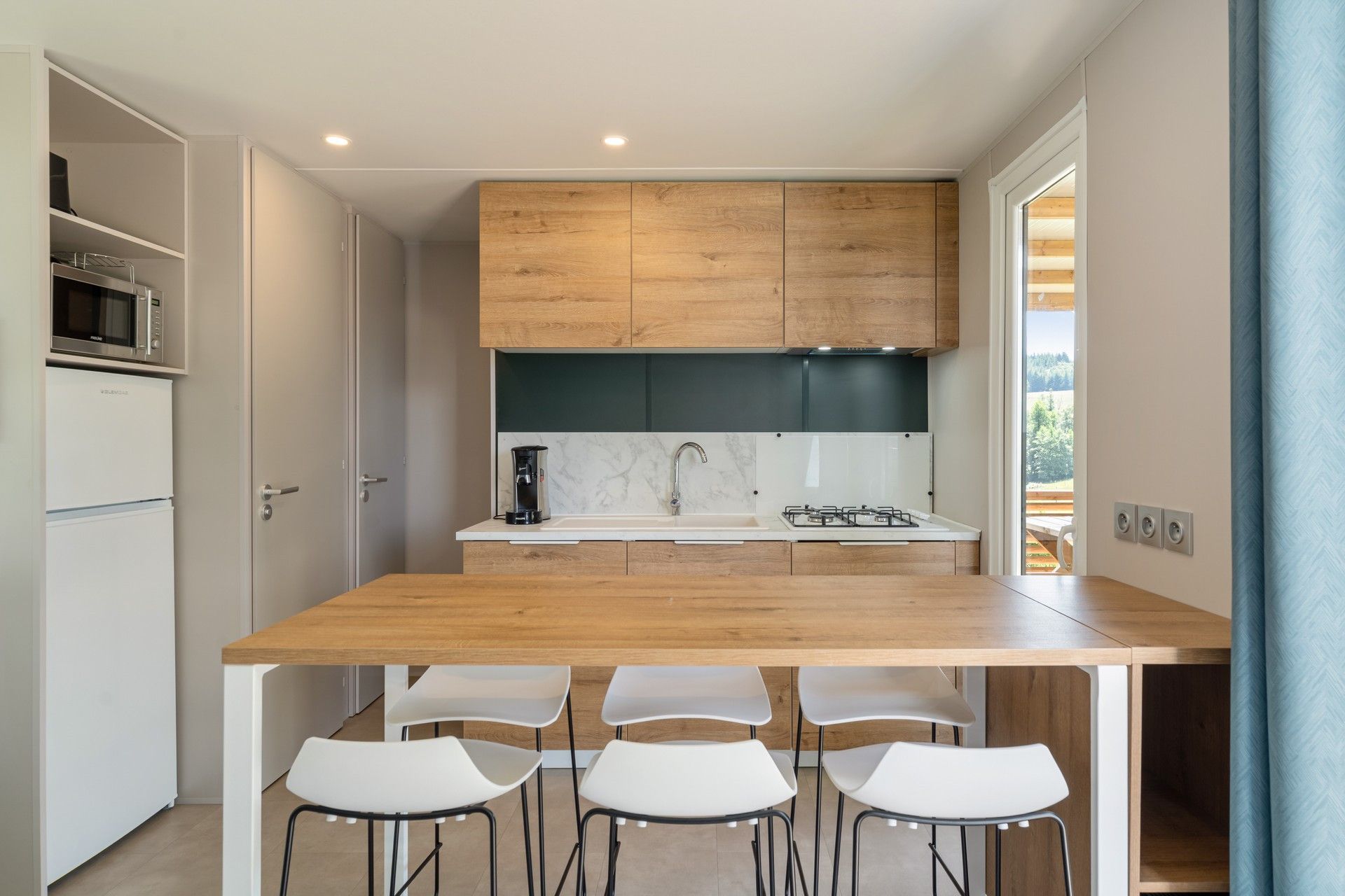 Una cocina moderna con encimera de madera, sillas blancas y estufa integrada.