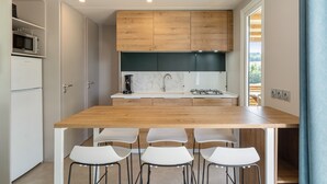 A modern kitchen with a wooden countertop, white chairs, and a built-in stove.