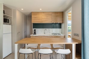 A modern kitchen with a wooden countertop, white chairs, and a built-in stove.