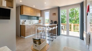 Une cuisine moderne dotée d’un îlot central, de tabourets de bar et d’un coin repas offrant une vue sur l’extérieur.