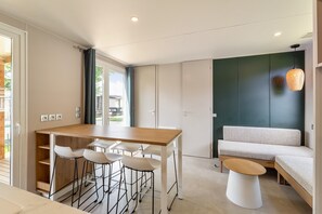 A modern kitchen with a dining area, a sofa, and a hanging light fixture.